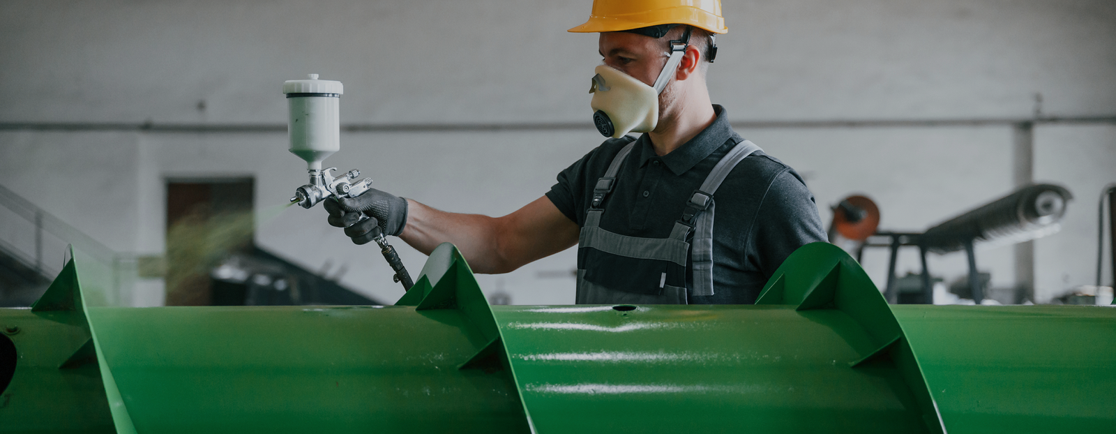 a man in uniform is in workstation painting an agriculture equipment
