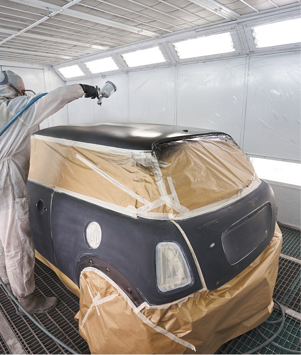 a man in uniform painting a car in a garage